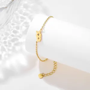 Polished gold stainless steel butterfly charm bracelet on white pedestal with water shadows