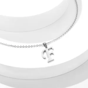 Vista macro di una collana in acciaio inossidabile argento con ciondolo a lettera F lucida