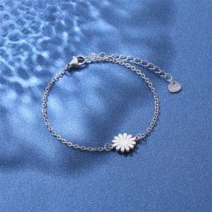 Macro shot of silver stainless steel chain bracelet featuring a white daisy pendant charm