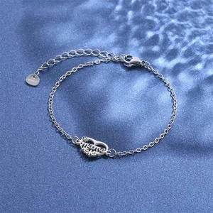 Detailed macro of silver stainless steel Mama pendant bracelet on blue textured surface