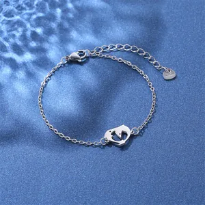 Macro shot of silver stainless steel chain bracelet featuring a hollow dolphin charm