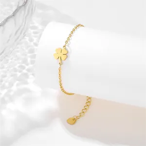 Detail of gold clover pendant and heart tag on adjustable stainless steel bracelet