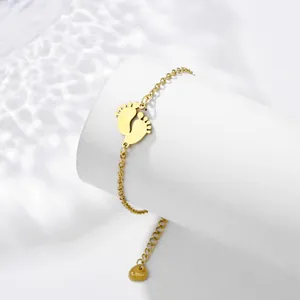 Detailed shot of golden stainless steel bracelet with twin baby feet charms on display