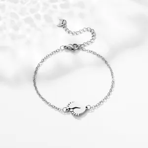 Macro detail of silver stainless steel chain bracelet with polished baby footprint charms