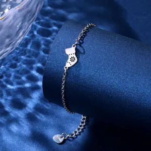 Polished silver stainless steel Christmas stocking pendant bracelet on blue background