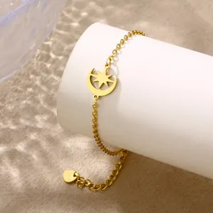 Detailed shot of gold moon and star pendant bracelet wrapped around white cylinder stand