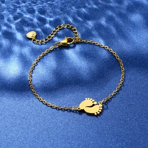 Detailed view of a golden baby footprint pendant bracelet on a blue silk water-ripple base