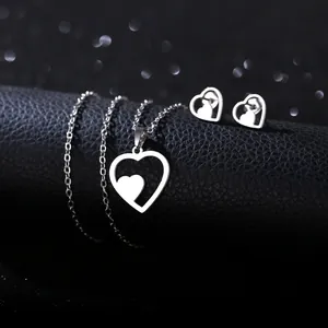 Polished stainless steel heart necklace and earrings set on a black leather display stand