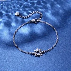 Close-up of stainless steel bracelet featuring sun pendant on blue water ripple background