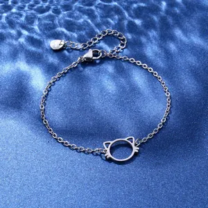 Detail of stainless steel bracelet with hollow cat charm on blue silk background