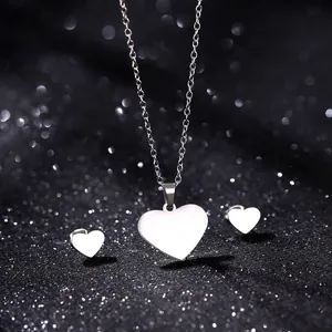 Polished stainless steel heart necklace and stud earrings set on a sparkly black background