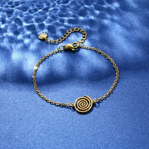Detail of gold stainless steel bracelet with spiral motif on blue water-ripple background
