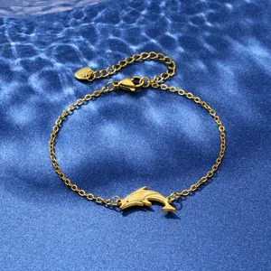 Detailed close-up of a golden dolphin pendant on a stainless steel chain on blue water waves