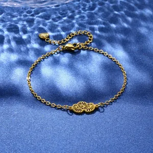 Detail of gold floral charm bracelet with dual cutout daisies and heart pendant