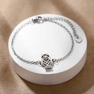 Bracelet chouette en acier poli avec chaîne ajustable sur un support de présentation