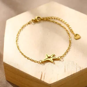 Polished gold stainless steel starfish charm bracelet with adjustable chain on wood base