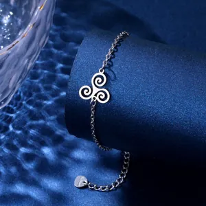 Detail of stainless steel bracelet with triskelion charm on blue textured display
