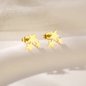 Polished gold stainless steel triple star cluster stud earrings on white ceramic base