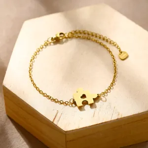 Detailed view of golden stainless steel jigsaw puzzle charm bracelet with heart cutout