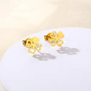 Golden clover-shaped stud earrings in polished stainless steel for women on a display