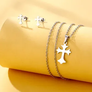 Close-up of silver stainless steel cross necklace and earring set on yellow background