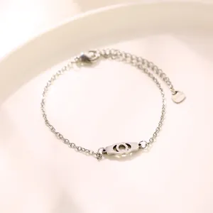 Minimalist stainless steel handcuff link bracelet with lobster clasp on ceramic plate