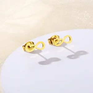 Detail of gold infinity heartbeat stud earrings on a round white display pedestal