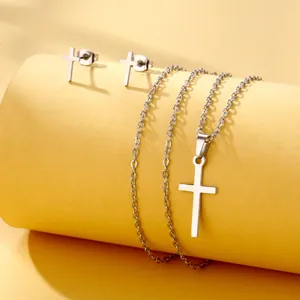 Detailed view of silver cross pendant necklace and stud earrings set on a pedestal