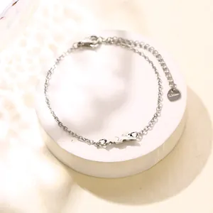 Minimalistische roestvrijstalen puppy-kettingarmband met dierenbedeltje op wit voetstuk