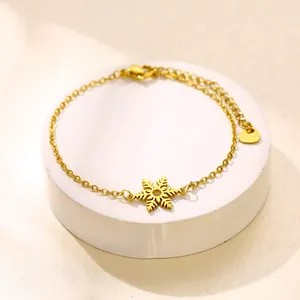 Bracelet flocon de neige en acier inoxydable doré sur un socle d'exposition blanc