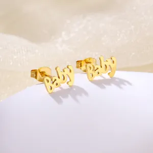 Macro shot of gold-plated stainless steel Baby letter stud earrings on a white stand
