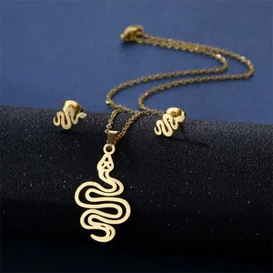 Detail of gold snake pendant necklace and stud earrings set on blue textured surface
