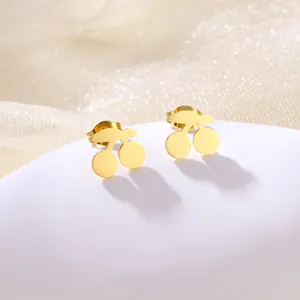 Macro shot of polished gold cherry stud earrings made of stainless steel on white pedestal