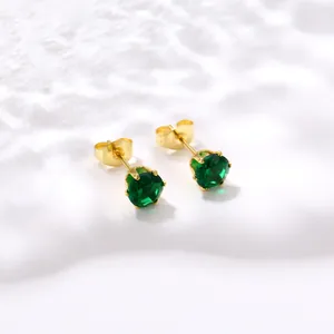 Gros plan de boucles d'oreilles couronne dorées avec zircons verts brillants