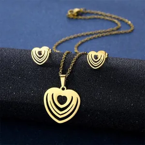 Detailed view of the layered heart pendant necklace and matching gold stud earring set
