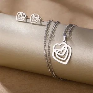 Polished stainless steel heart pendant necklace and stud earrings set on gold pedestals