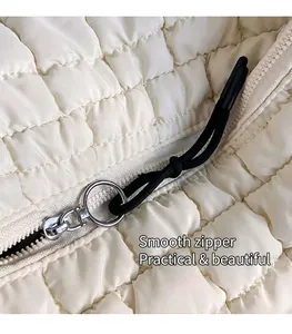Detail of silver smooth zipper and black braided puller on white quilted cloud bag