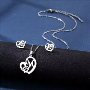 Detail view of silver heart pendant and earrings with Mom engraving on blue fabric