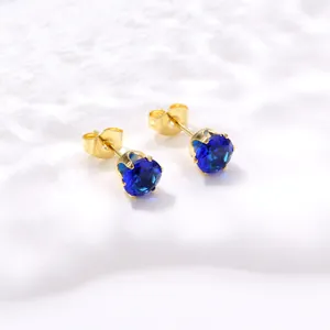 Détails macro de boucles d'oreilles couronne en zircon bleu roi et griffes dorées