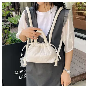 Detailed close-up of a white puffy nylon drawstring backpack with soft quilted texture