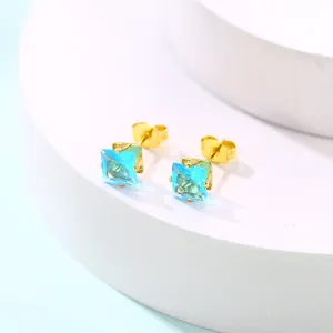 Détail macro de boucles d'oreilles carrées en zircon bleu ciel serties de quatre griffes d'or