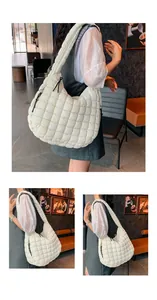 Close-up of white quilted puffer bag featuring a decorative black knot and shoulder strap