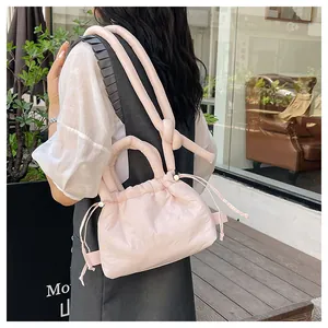Detail of light pink puffer bag featuring drawstring closure and knotted handle texture