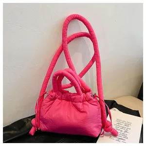 Detail of hot pink quilted puffer handbag with padded handles and knotted side cord