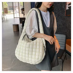 Detailed view of cream quilted puffer bag with lattice texture worn by a model