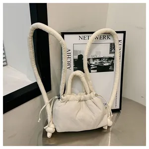 Detail view of a cream quilted drawstring backpack on a metal table with minimalist background