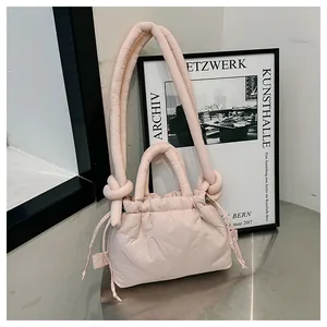 Detail of light pink quilted drawstring bag with knotted strap on minimalist background