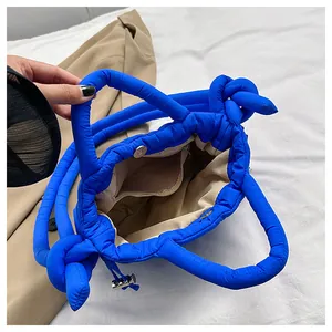 Detail view of bright blue quilted bag showing magnetic closure and interior pocket