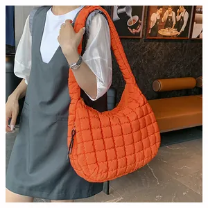 Detail of bright orange quilted puffer bag showing large grid stitching and soft texture