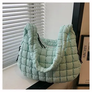 Detail of mint green quilted cloud bag featuring puff texture and white zipper closure